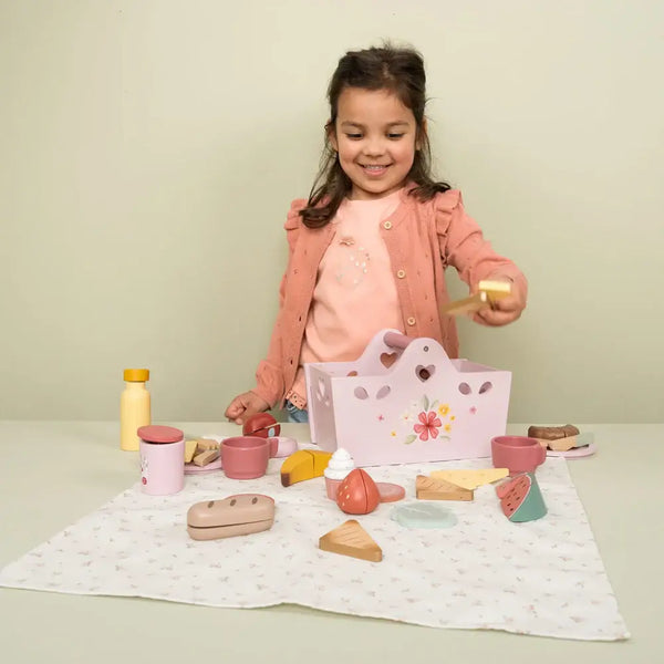 Little Dutch wooden picnic set with girl playing happily, showcasing various food items and drinks on a picnic blanket.