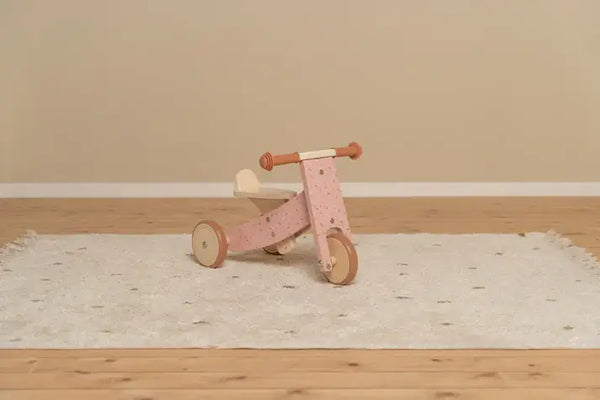 Little Dutch pink wooden tricycle on a white rug, perfect for young children to develop motor skills and enjoy safe rides.