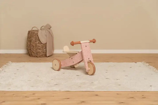 Little Dutch wooden pink tricycle on a soft rug, perfect for young children's motor skill development.