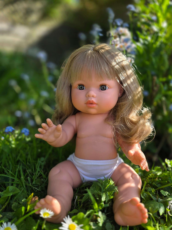Mini Colettos doll Kate with blonde hair and blue eyes, sitting in a field of flowers.