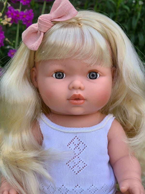 Mini Colettos, Sage (Light Blonde Hair with Blue Eyes) doll with a pink bow and blonde hair.