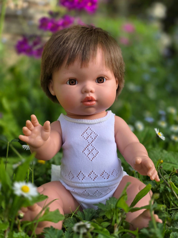 Dolls Vest and Pants Set in White displayed on a Mini Colettos doll sitting in a flower-filled garden.