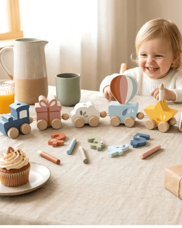 Happy child playing with Speedy Monkey, Birthday Train toy set featuring colorful carriages and decorations.