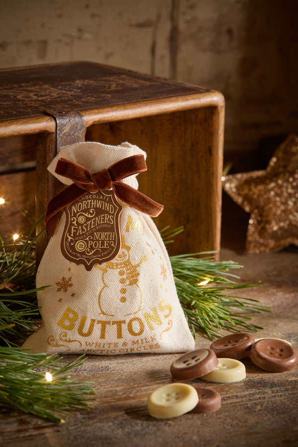 The Chocolate Gift Company - Snowman Buttons pouch with chocolate buttons on wood and greenery background.