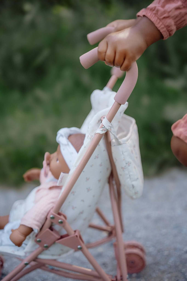 Child pushing a Little Dutch Metal Doll Stroller with a cute doll, featuring a lovely White Meadows design.