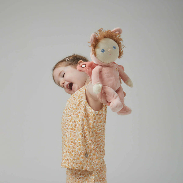 Little girl joyfully holding Millie Moth doll in a peachy-pink outfit, showcasing playful cuddle-time magic.