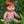 Mini Colettos, Jasper (Boy Doll with Brown Eyes & Red Hair) sitting in grass surrounded by flowers.