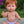 Mini Colettos, Jasper (Boy Doll with Brown Eyes & Red Hair) sitting in a garden with a cheerful expression.