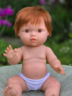 Mini Colettos, Jasper (Boy Doll with Brown Eyes & Red Hair) sitting in a garden with a cheerful expression.