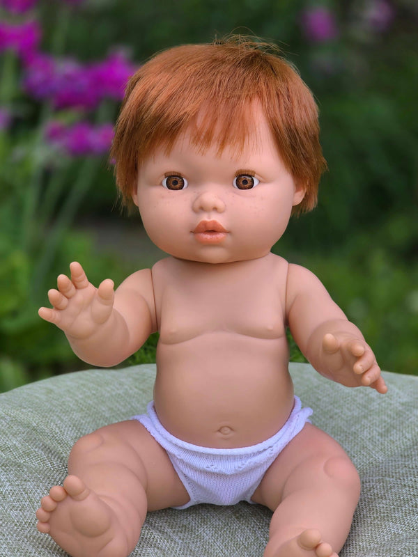 Mini Colettos, Jasper (Boy Doll with Brown Eyes & Red Hair) sitting outdoors with a cheerful expression.
