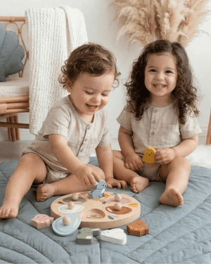 Two toddlers joyfully playing with the Speedy Monkey, Garden Surprise Puzzle, unveiling colorful wooden animals.