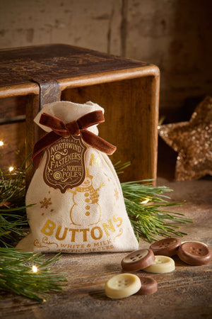 The Chocolate Gift Company - Snowman Buttons pouch with chocolate buttons on wood and greenery background.
