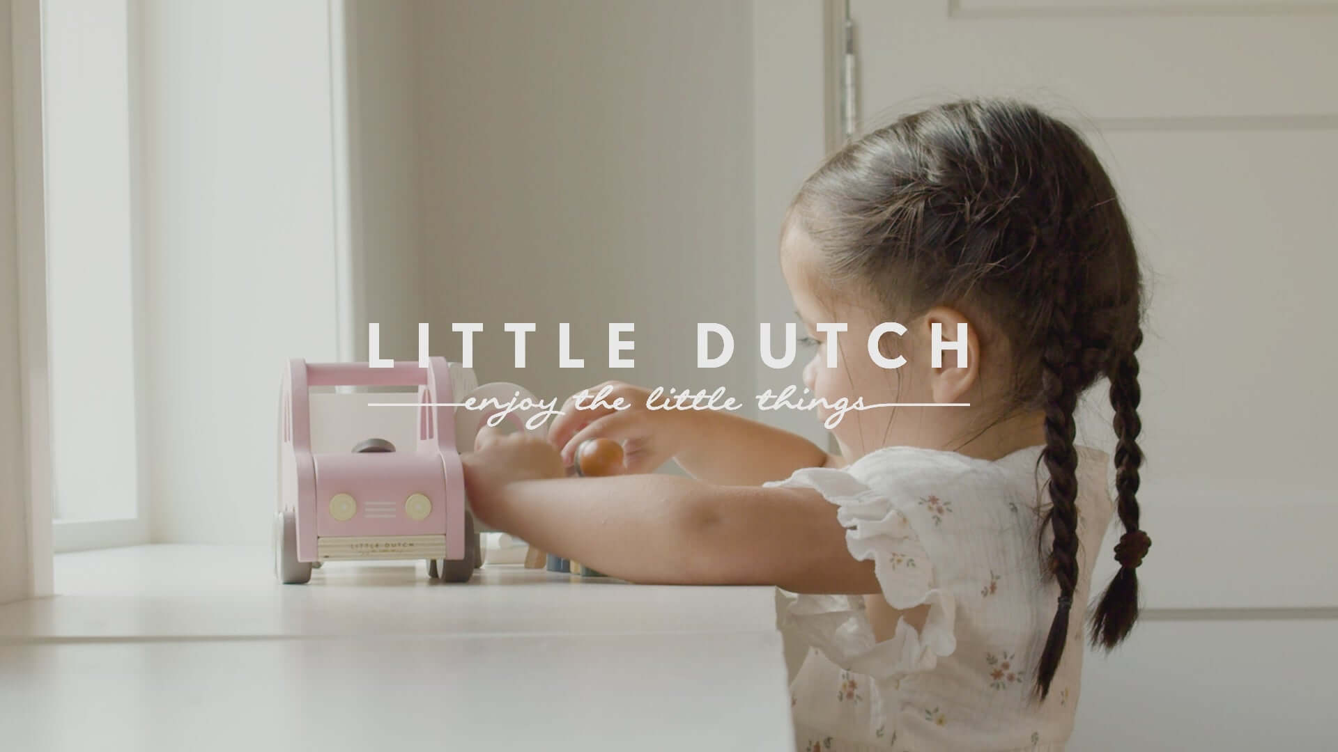 Little Dutch pink toy car and caravan set being played with by a child, encouraging imaginative adventures.
